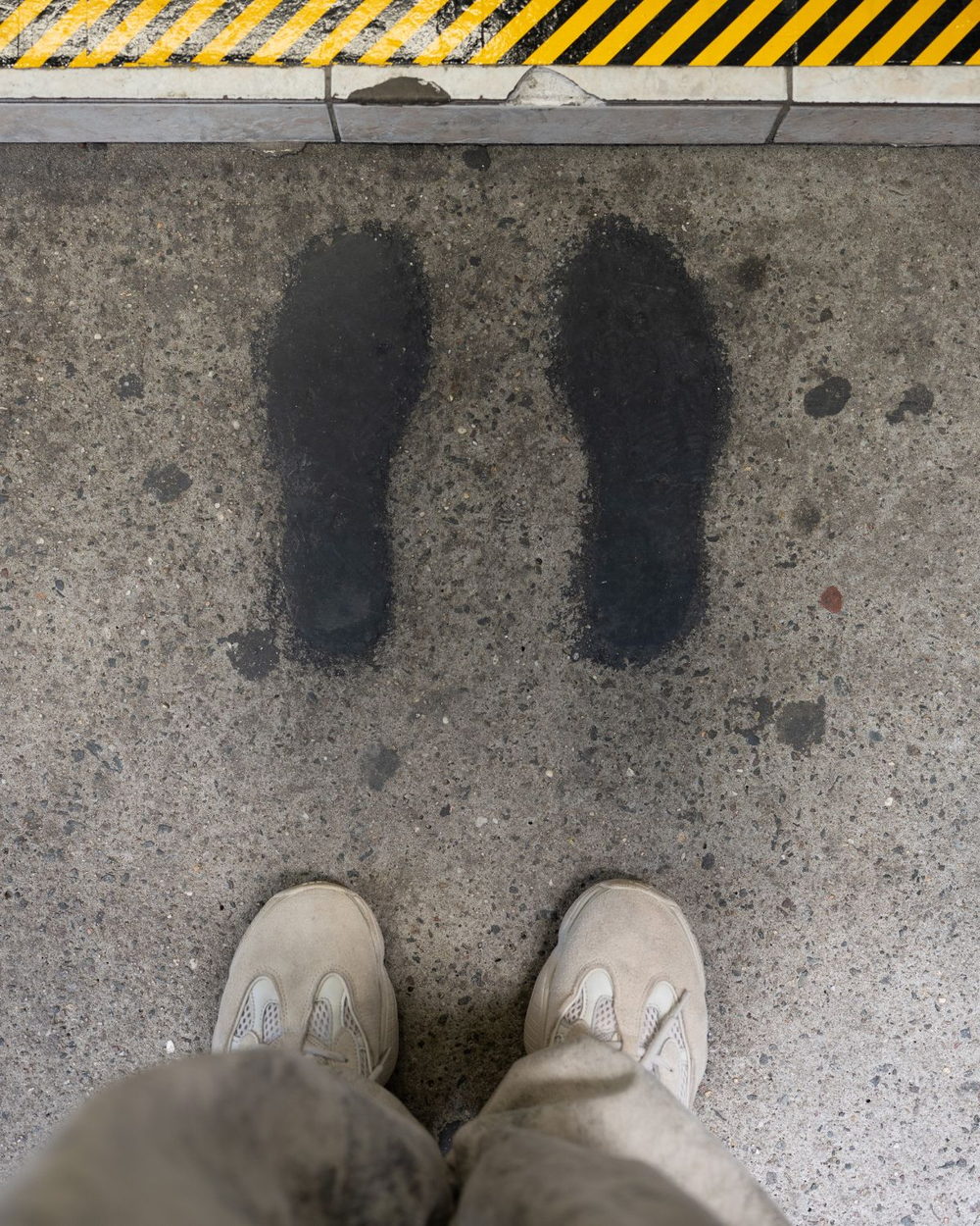Two painted footprints on the sidewalk in front of the window, where you stand to order